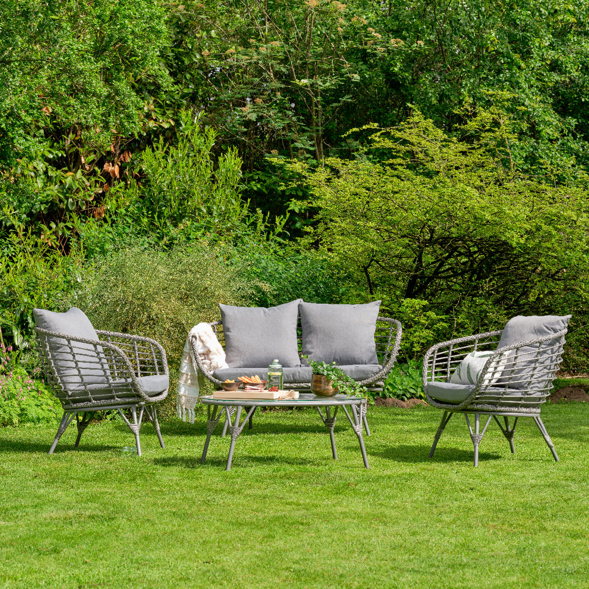 Outdoor patio set with chairs and table on a grassy area with trees in the background
